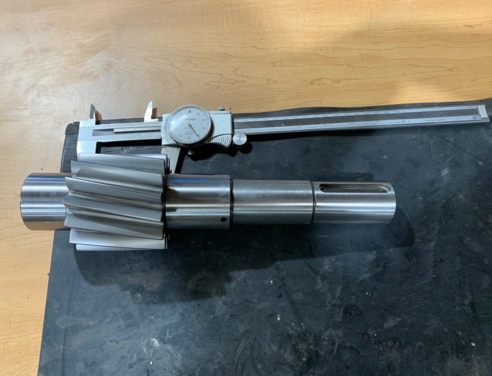 A repaired pinion shaft measured with a dial caliper during inspection