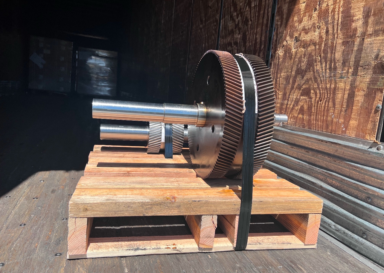 Two large helical bull gears with freshly cut teeth on their pinion shafts