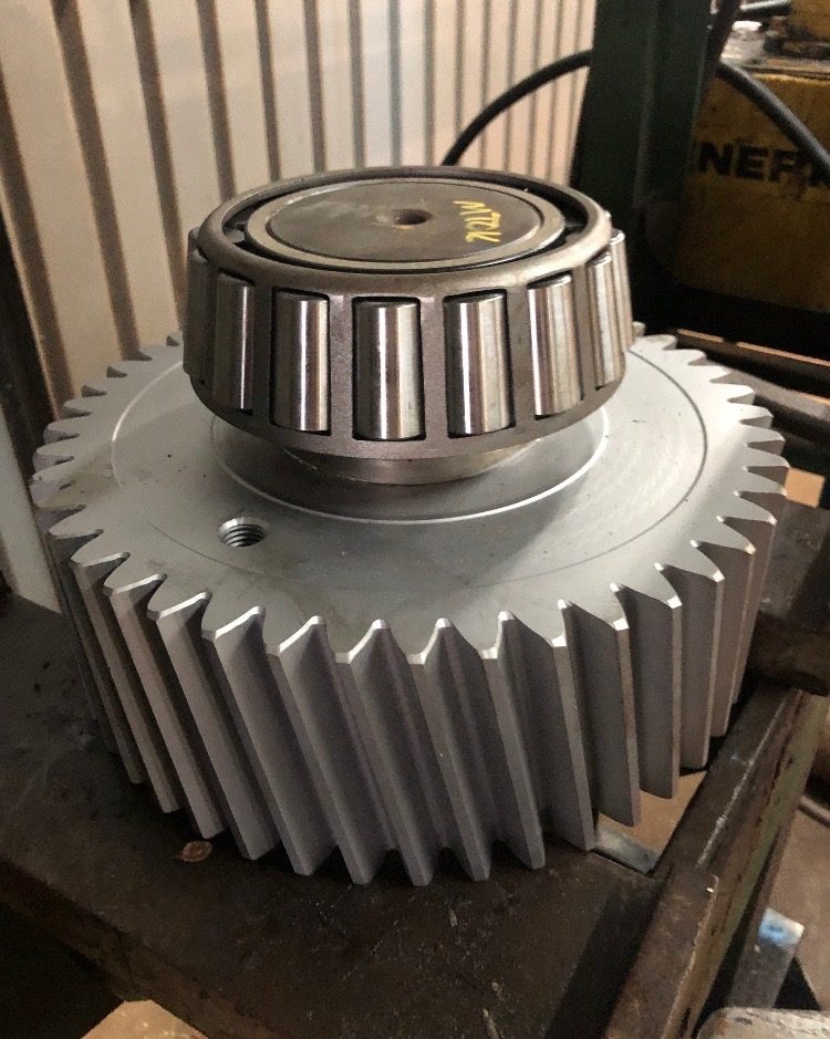 Reconditioned helical gear with a new tapered roller bearing seated on top