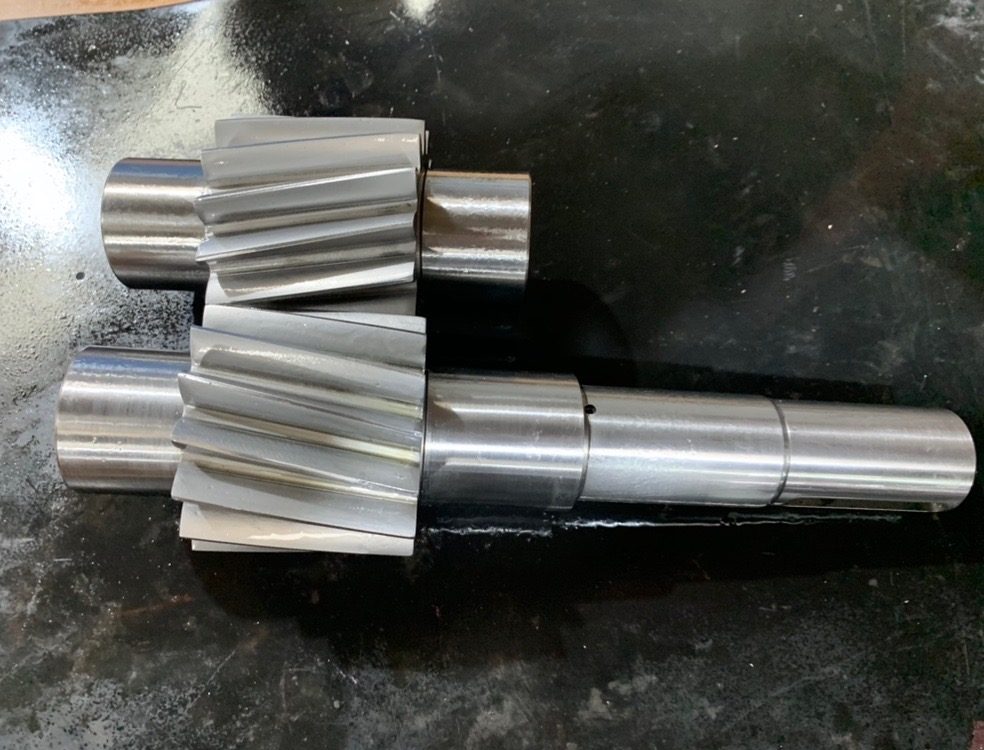 Two remanufactured helical pinion shafts with freshly cut teeth