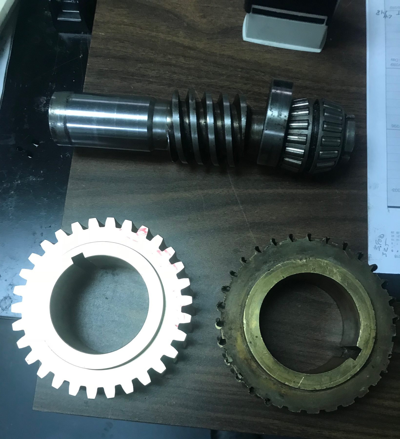 A worm shaft beside a newly cut steel worm wheel and the worn bronze worm wheel it replaces